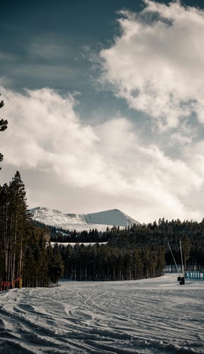 Ski slope with mountain peak and pine trees under dramatic clouds in Winter Park, Colorado