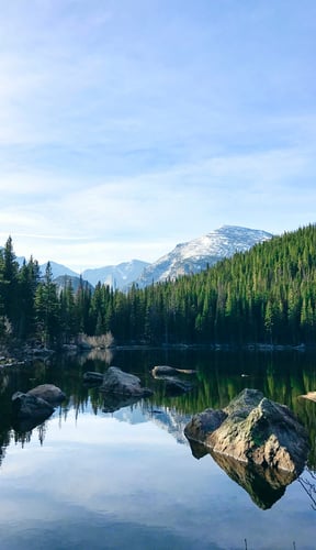 Still mountain lake reflecting pine forest and snow-capped peaks near Granby, Colorado