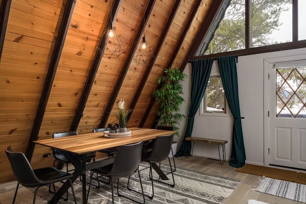 Open-plan living room with kitchen, stone fireplace, vaulted ceiling, and wood railings overlooking lower level